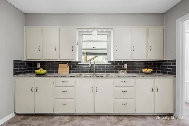 a kitchen with granite countertop white cabinets and sink
