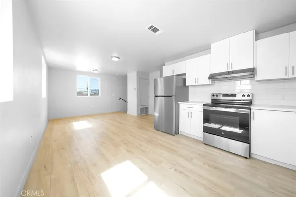 a kitchen with a refrigerator and white cabinets