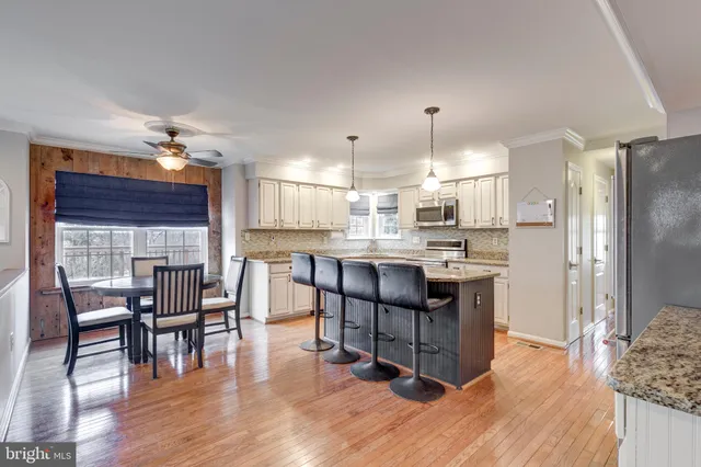 a kitchen with stainless steel appliances kitchen island granite countertop a table chairs and a refrigerator