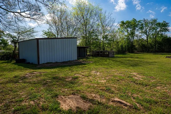 a view of a backyard with large trees and wooden fence