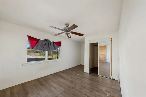 an empty room with wooden floor ceiling fan and windows
