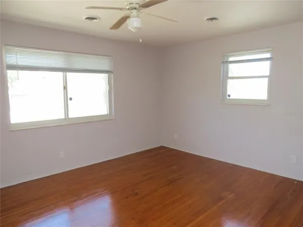 an empty room with wooden floor and windows
