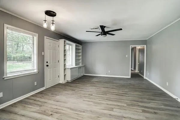 a view of empty room with wooden floor and fan