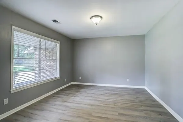 a view of an empty room with wooden floor and a window