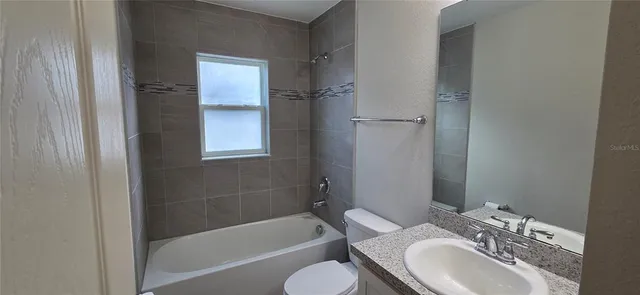 a bathroom with a granite countertop toilet a sink and a bathtub