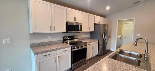 a kitchen with stainless steel appliances granite countertop a stove a sink dishwasher and a refrigerator with wooden cabinets