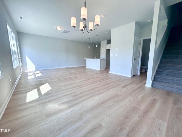 a view of an empty room with wooden floor and staircase