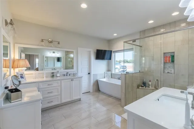 a large white bathroom with a tub sink shower and mirror