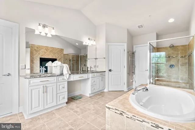 a spacious bathroom with a granite countertop sink a large mirror and a bathtub