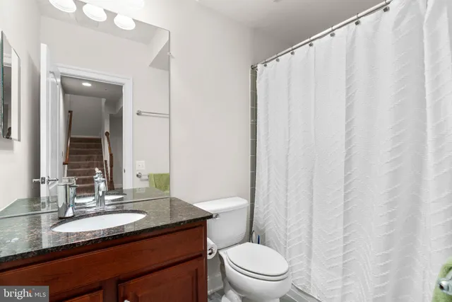 a bathroom with a granite countertop sink toilet and a mirror