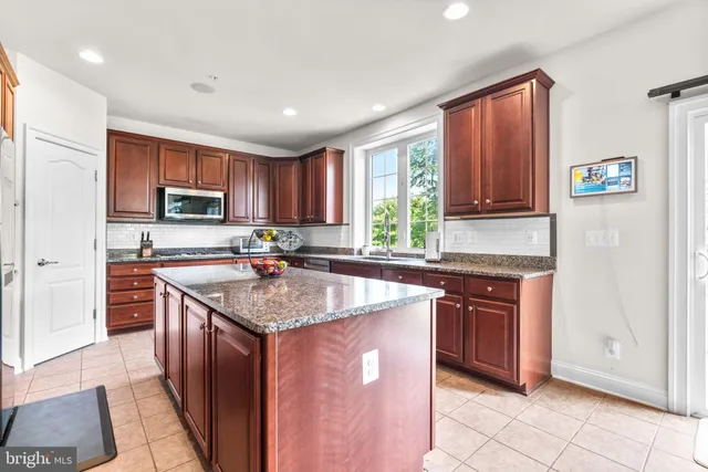 a kitchen with stainless steel appliances granite countertop a stove sink microwave and window