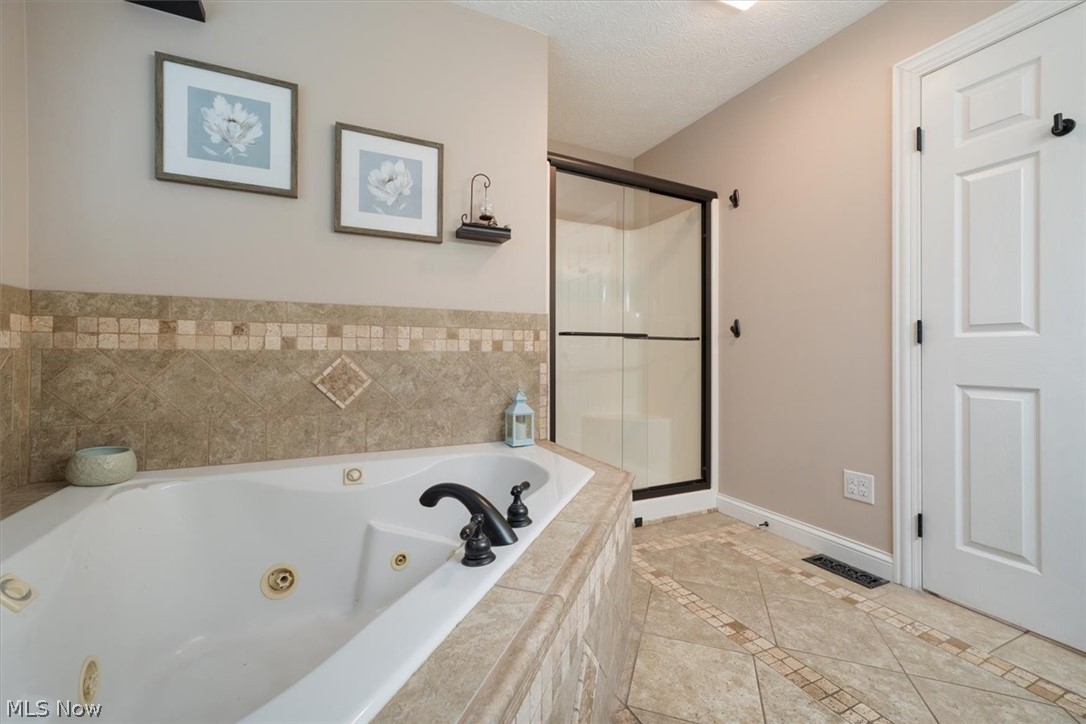24876 Quarry Road Wellington, OH 44090 - Photo 24 of 50 Bathroom featuring a textured ceiling, tile flooring, and separate shower and tub