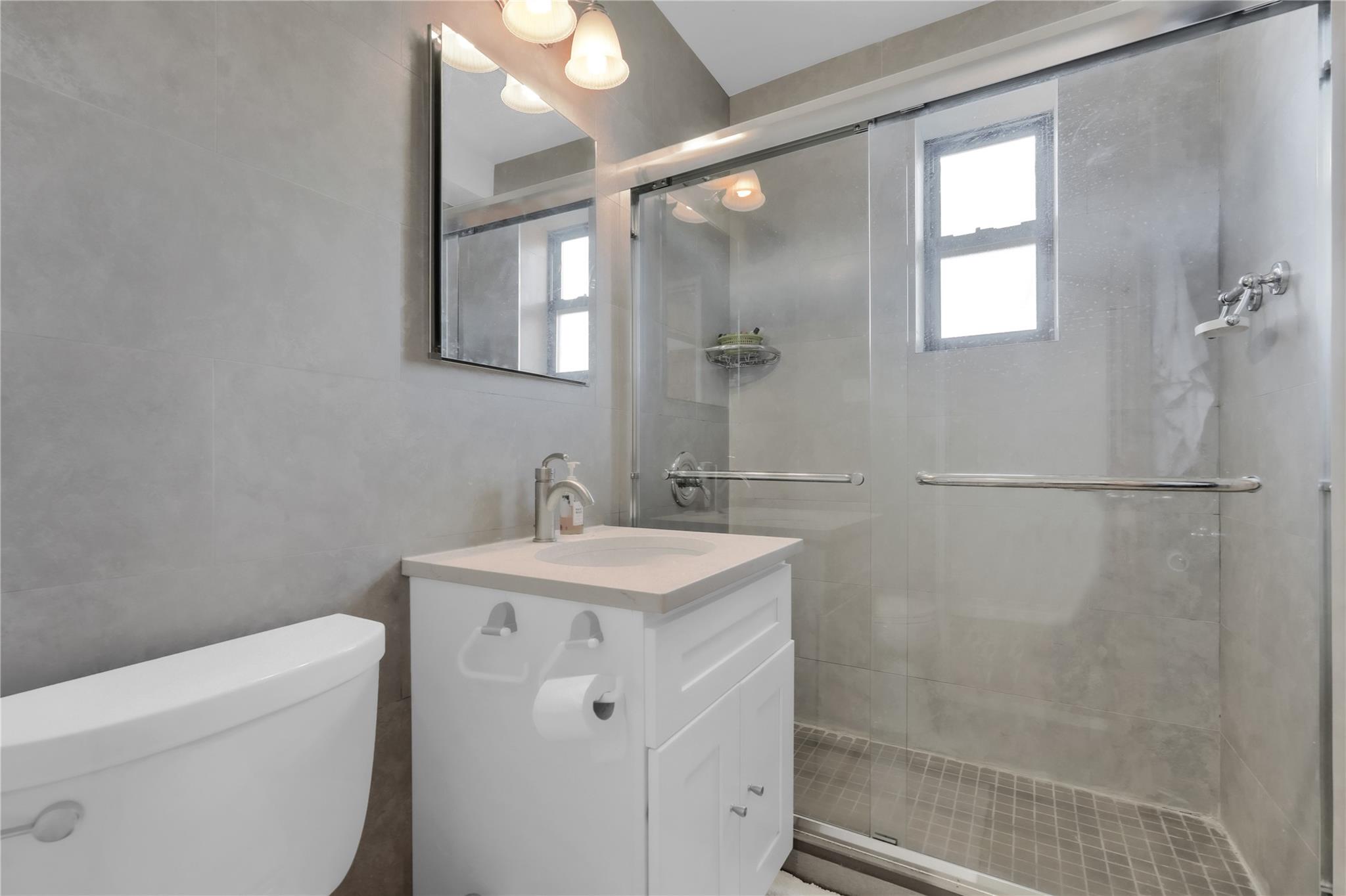139-09 28th Road, Unit 6F Queens, NY 11354 - Photo 11 of 14 Bathroom featuring tile walls, vanity, and a stall shower