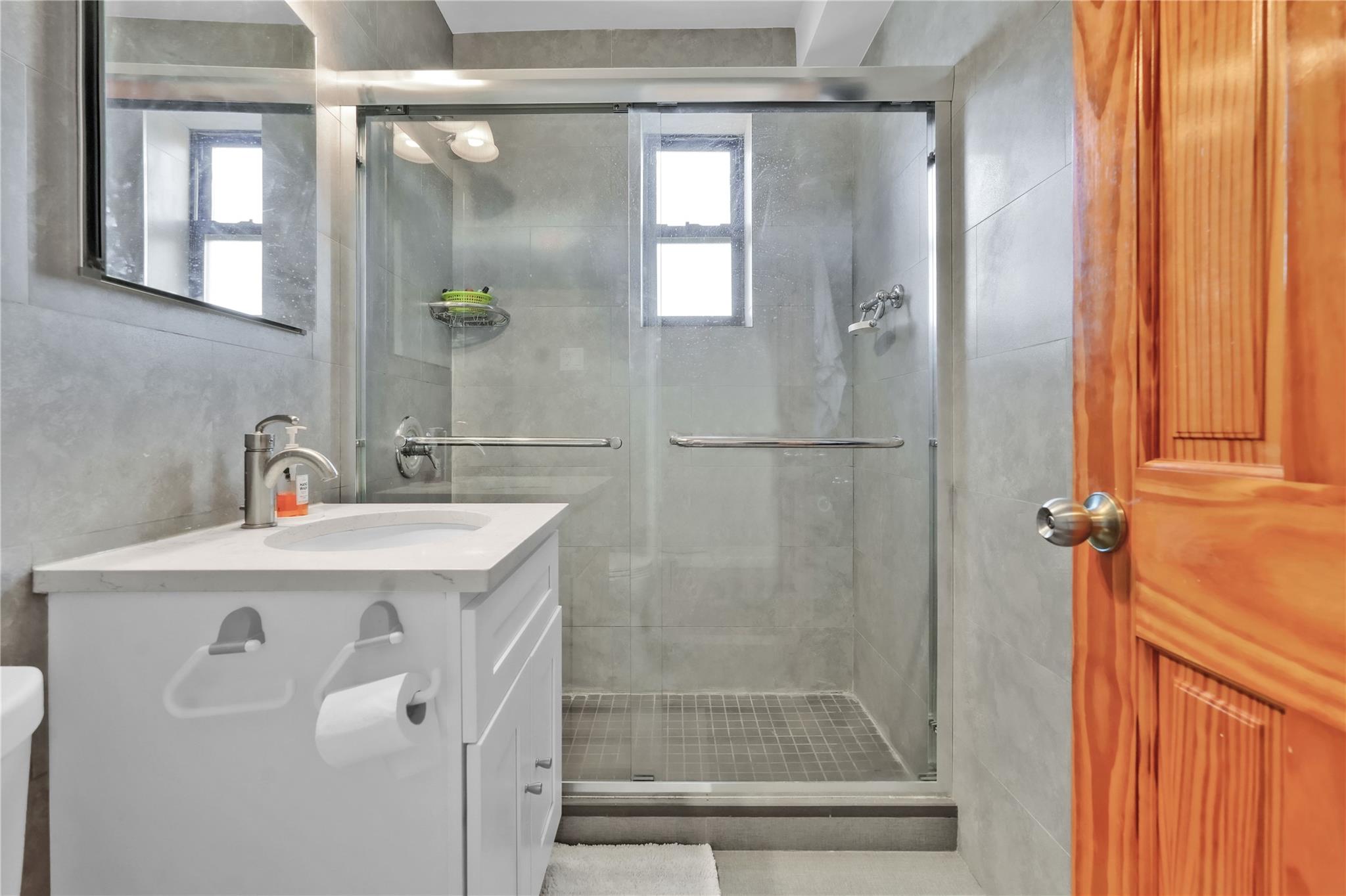 139-09 28th Road, Unit 6F Queens, NY 11354 - Photo 12 of 14 Full bathroom featuring vanity, a stall shower, and tile walls