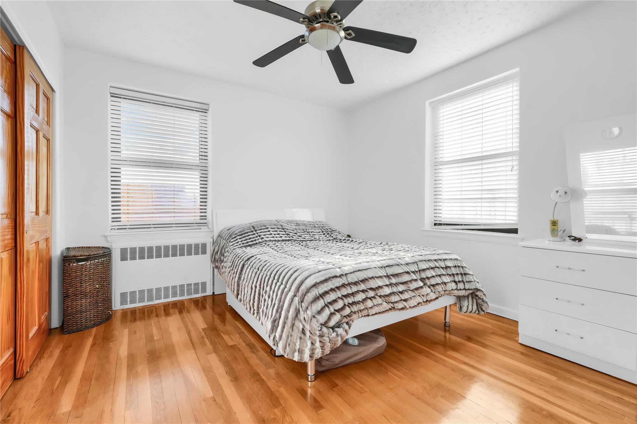 139-09 28th Road, Unit 6F Queens, NY 11354 - Photo 6 of 14 Bedroom with radiator, hardwood / wood-style floors, a ceiling fan, and a closet