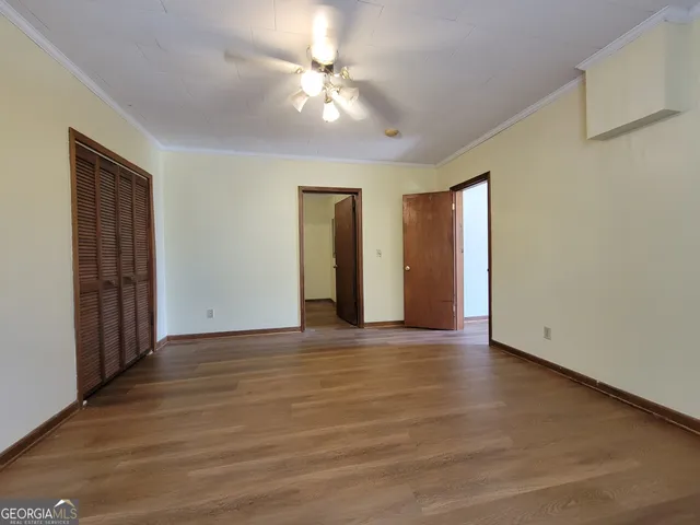 a view of an empty room with window and wooden floor