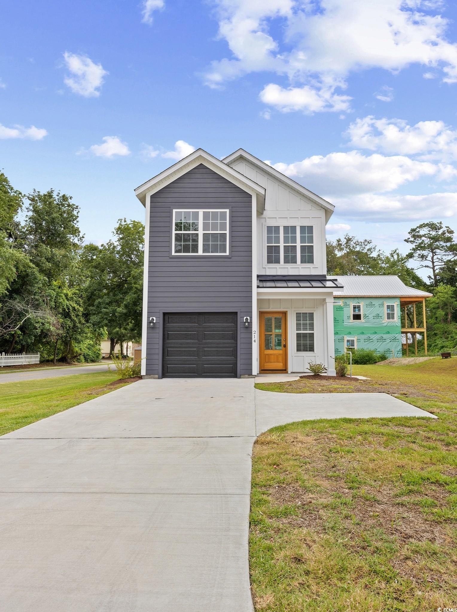View of front of house featuring a metal roof, concrete driveway, a standing seam roof, board and batten siding, and a garage