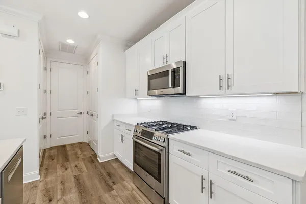 a kitchen with stainless steel appliances white cabinets and a stove top oven