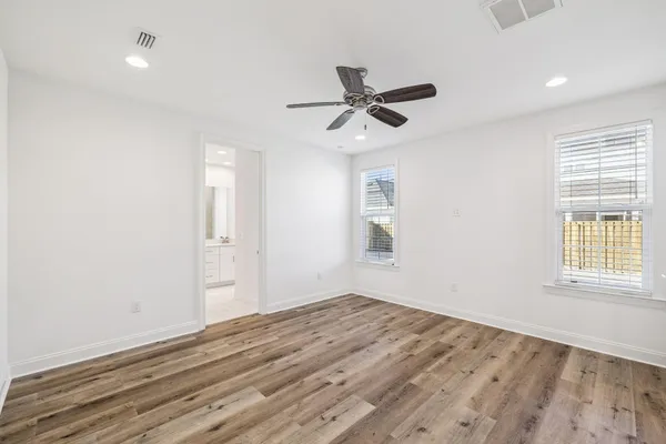 a view of empty room with wooden floor and ceiling fan