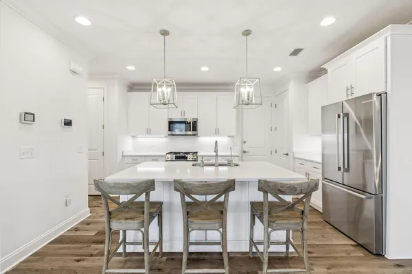 a kitchen with stainless steel appliances kitchen island granite countertop a dining table chairs and white cabinets