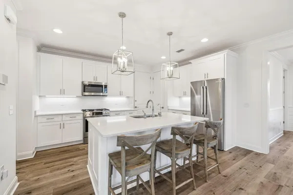 a kitchen with stainless steel appliances kitchen island granite countertop a table chairs stove and white cabinets