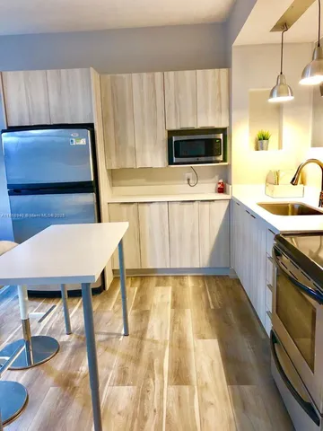 a kitchen with stainless steel appliances a stove a microwave a sink a stove and white cabinets