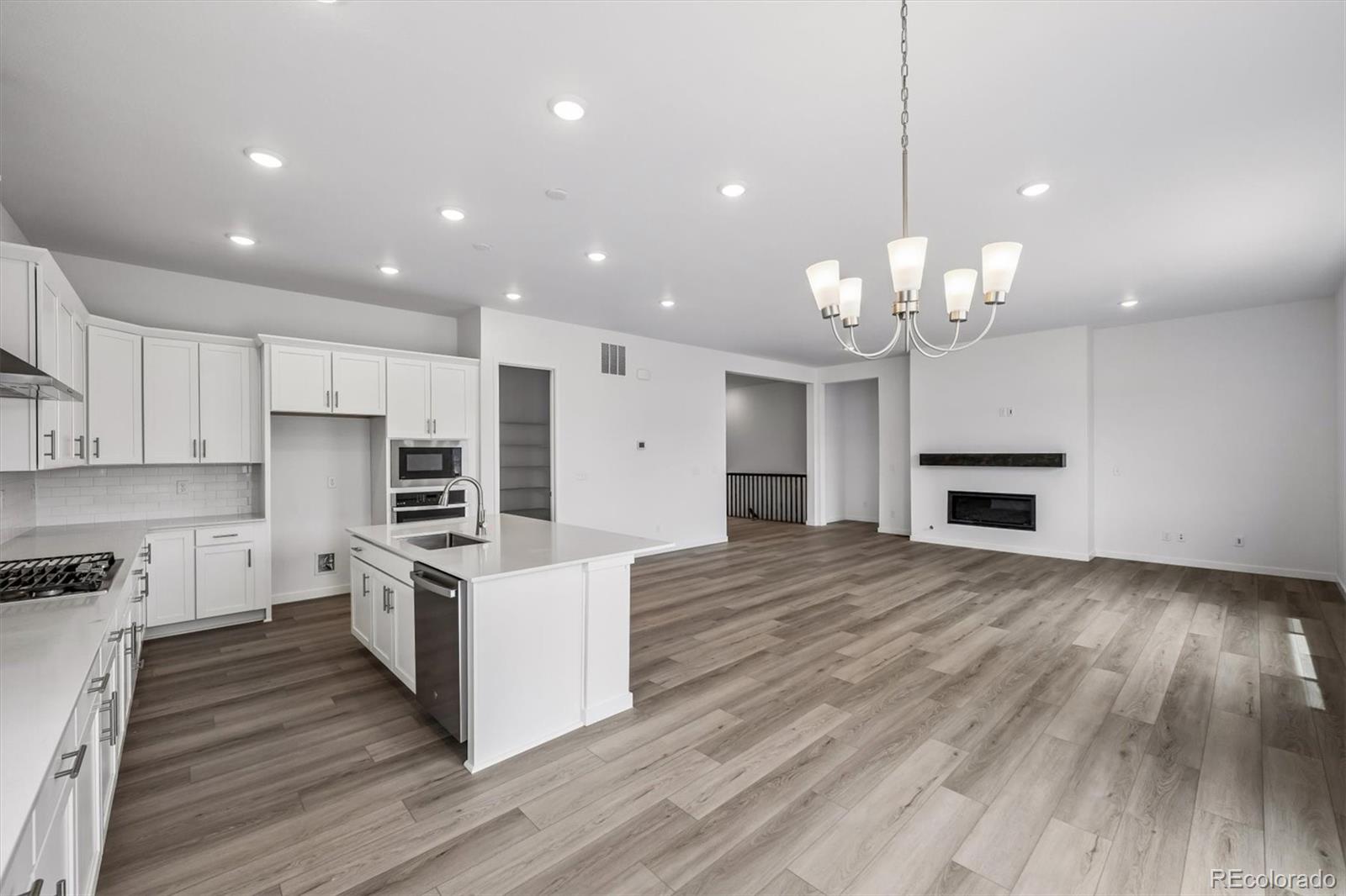 2516 West Bitterroot Place Highlands Ranch, CO 80129 - Photo 13 of 24 a large kitchen with kitchen island a stove a sink dishwasher a refrigerator and white cabinets with wooden floor