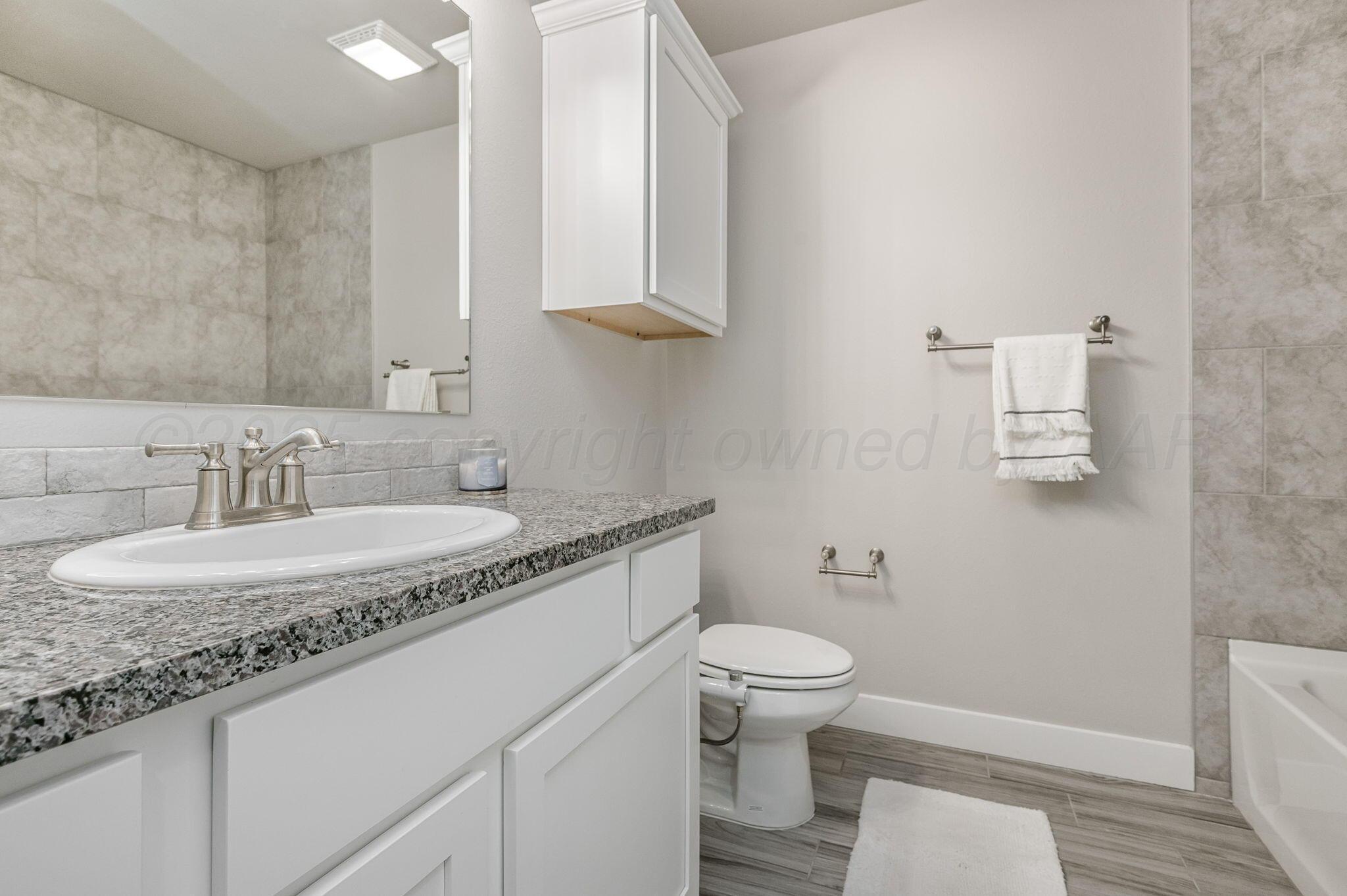 9209 Lexford Drive Amarillo, TX 79119 - Photo 19 of 23 a bathroom with a granite countertop sink a toilet and a mirror