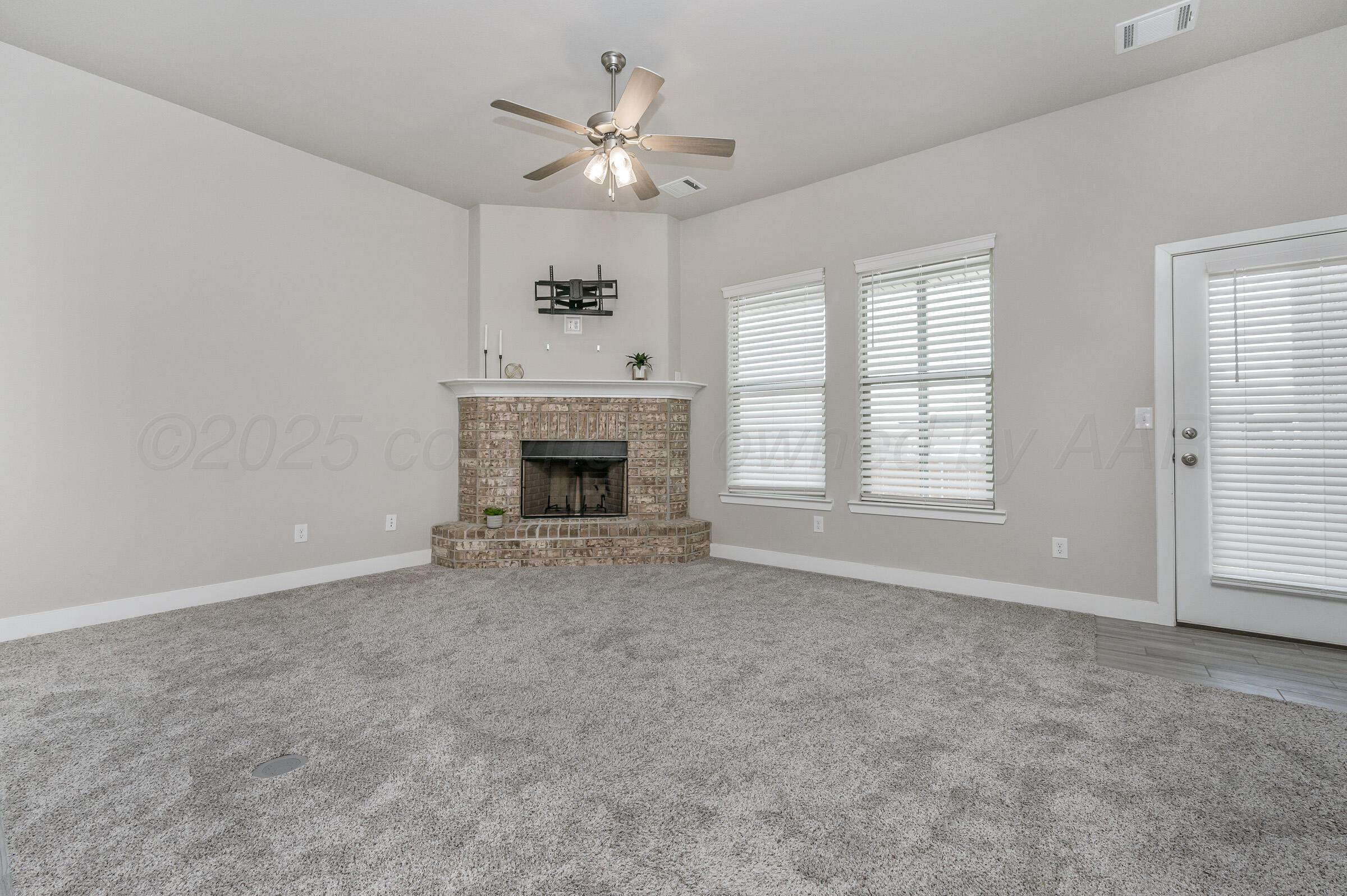 9209 Lexford Drive Amarillo, TX 79119 - Photo 8 of 23 an empty room with windows fireplace and fan