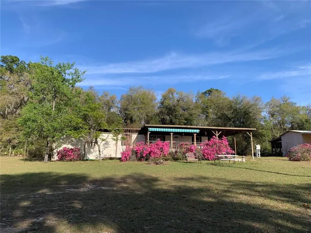 a view of a patio with table and chairs under an umbrella with a big yard