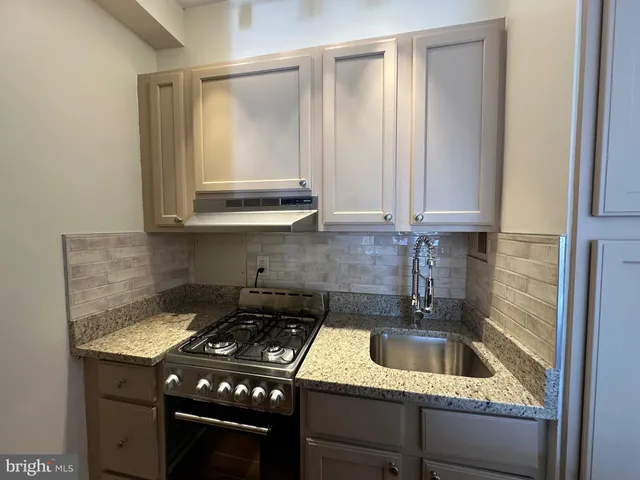 a kitchen with a sink a stove and cabinets