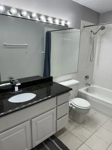 a bathroom with a granite countertop sink a toilet a mirror and shower