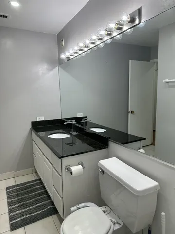 a bathroom with a granite countertop toilet sink and mirror