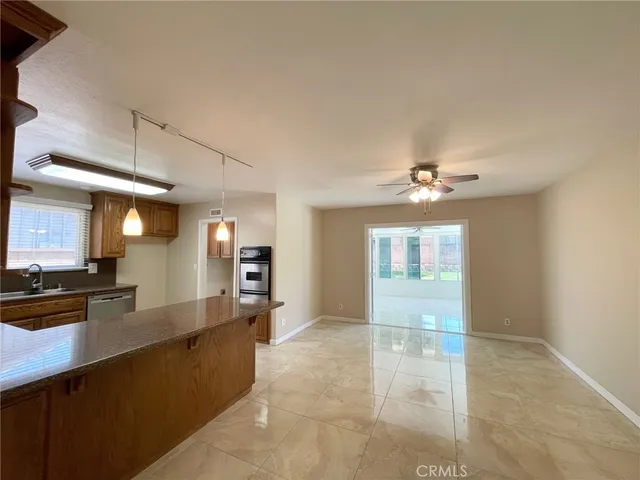 a large living room with stainless steel appliances kitchen island granite countertop a large window and a fireplace