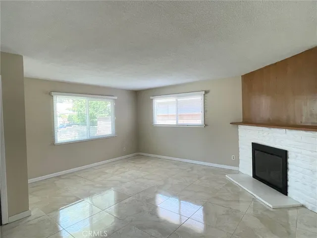 a view of an empty room with a fireplace and a window