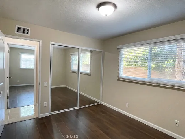 a view of an empty room with window and wooden floor