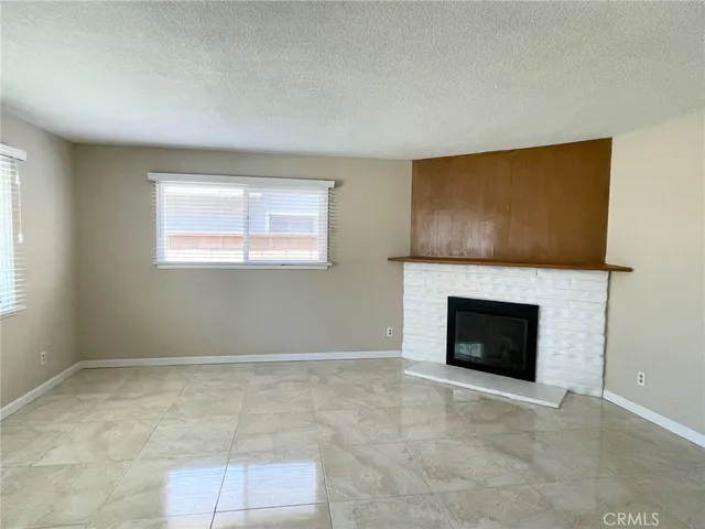 a view of an empty room with a fireplace and a window