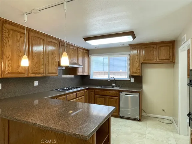a kitchen with kitchen island granite countertop a sink a counter top space appliances and cabinets