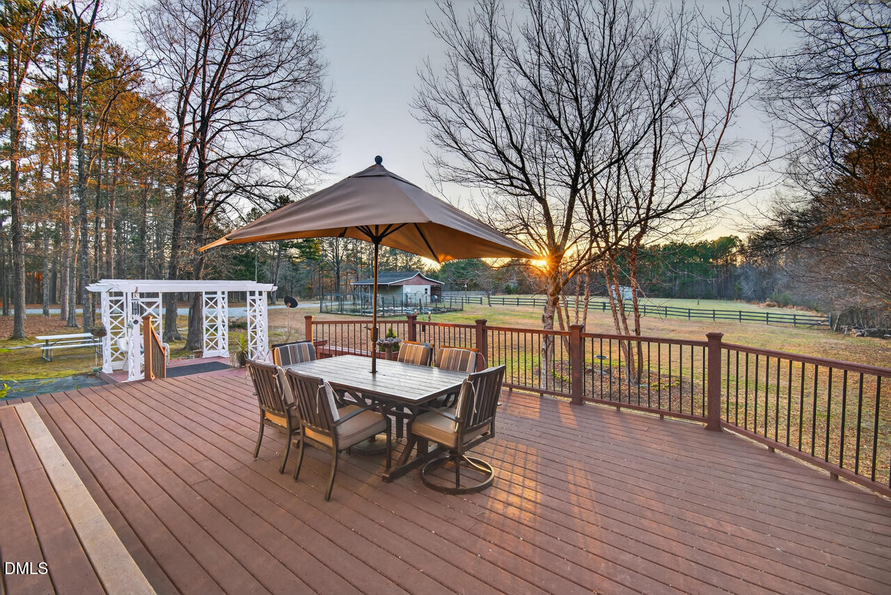 10775 Buffalo Creek Road Rougemont, NC 27572 - Photo 20 of 65 a view of a roof deck with table and chairs under an umbrella with wooden floor