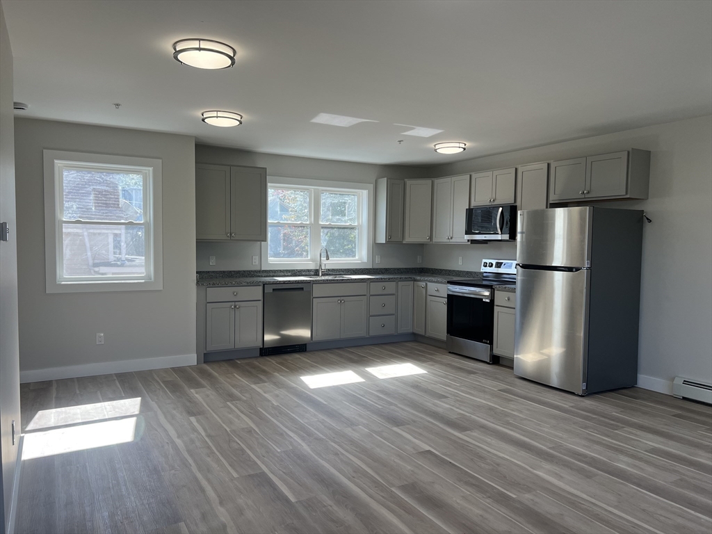 151 Shepard Street, Unit 14 Lynn, MA 01902 - Photo 2 of 22 a kitchen with stainless steel appliances granite countertop a refrigerator a sink dishwasher a stove with wooden floors and cabinets