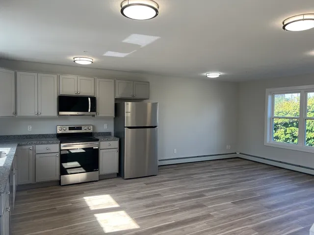 a kitchen with granite countertop a refrigerator and a stove top oven
