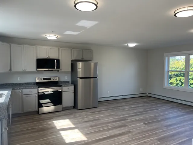 a kitchen with granite countertop a refrigerator and a stove top oven