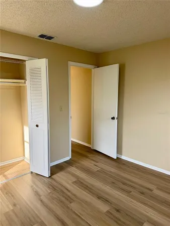 a view of an empty room with wooden floor and closet