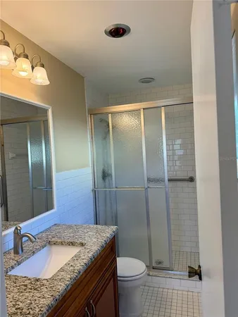 a bathroom with a granite countertop sink toilet and shower