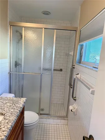 a bathroom with a granite countertop sink toilet and shower
