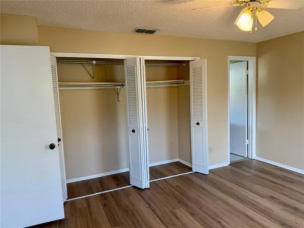 a view of empty room with wooden floor and fan