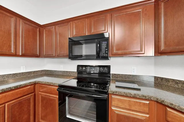 a kitchen with granite countertop wood cabinets and stainless steel appliances