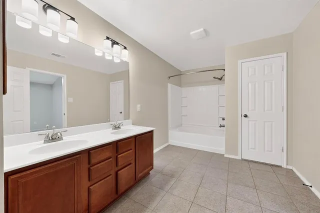 a bathroom with a double vanity sink mirror and bathtub