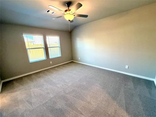 an empty room with windows and ceiling fan