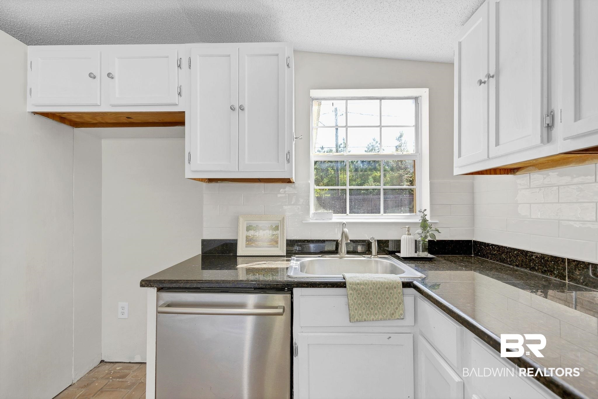 11964 Stroh Road Daphne, AL 36527 - Photo 18 of 58 Kitchen with stainless steel dishwasher, white cabinets, a sink, and dark countertops
